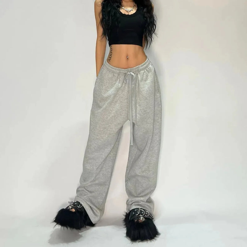 Person wearing gray sweatpants with fluffy black shoes on a plain background