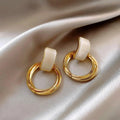 WOLZI Opaline Halo Drop Earrings featuring cream enamel and gold-toned hoops on satin fabric