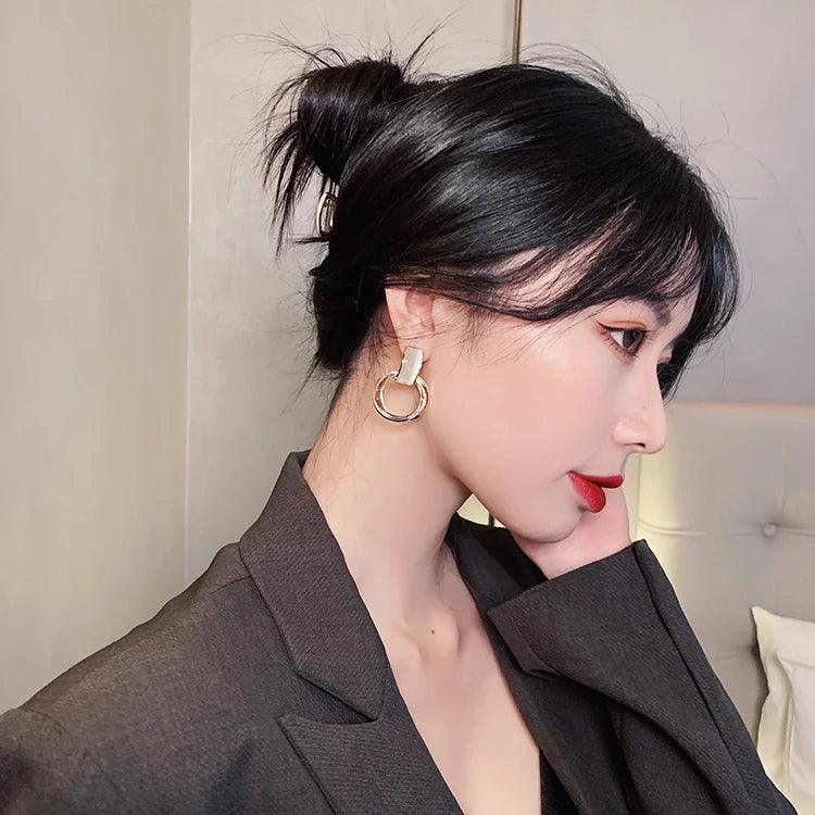 A woman wearing WOLZI Opaline Halo Drop Earrings and a dark blazer.