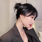 A woman wearing WOLZI Opaline Halo Drop Earrings and a dark blazer.