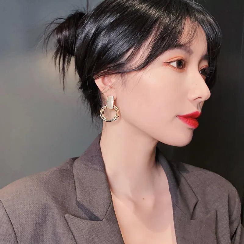 Model wearing WOLZI Opaline Halo Drop Earrings with gold hoop and rectangular detail.