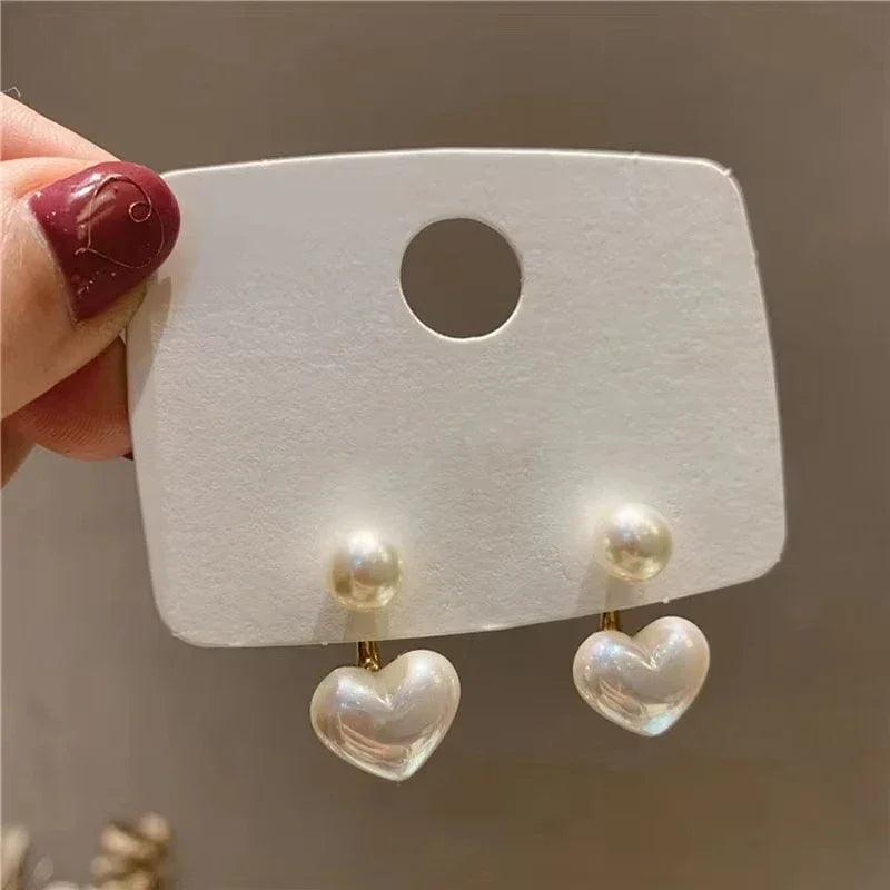 Amelie Heart Pearl Earrings by WOLZI featuring white pearl studs and heart charms