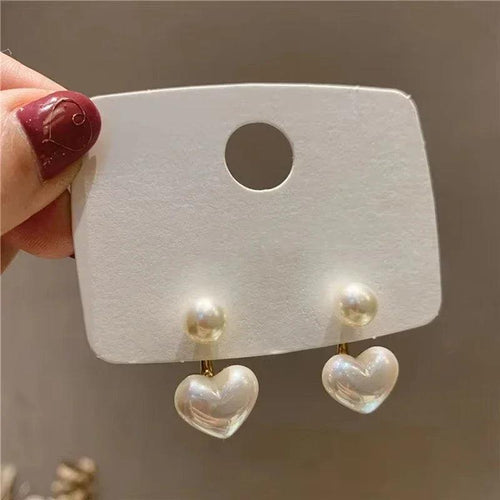 Amelie Heart Pearl Earrings by WOLZI featuring white pearl studs and heart charms
