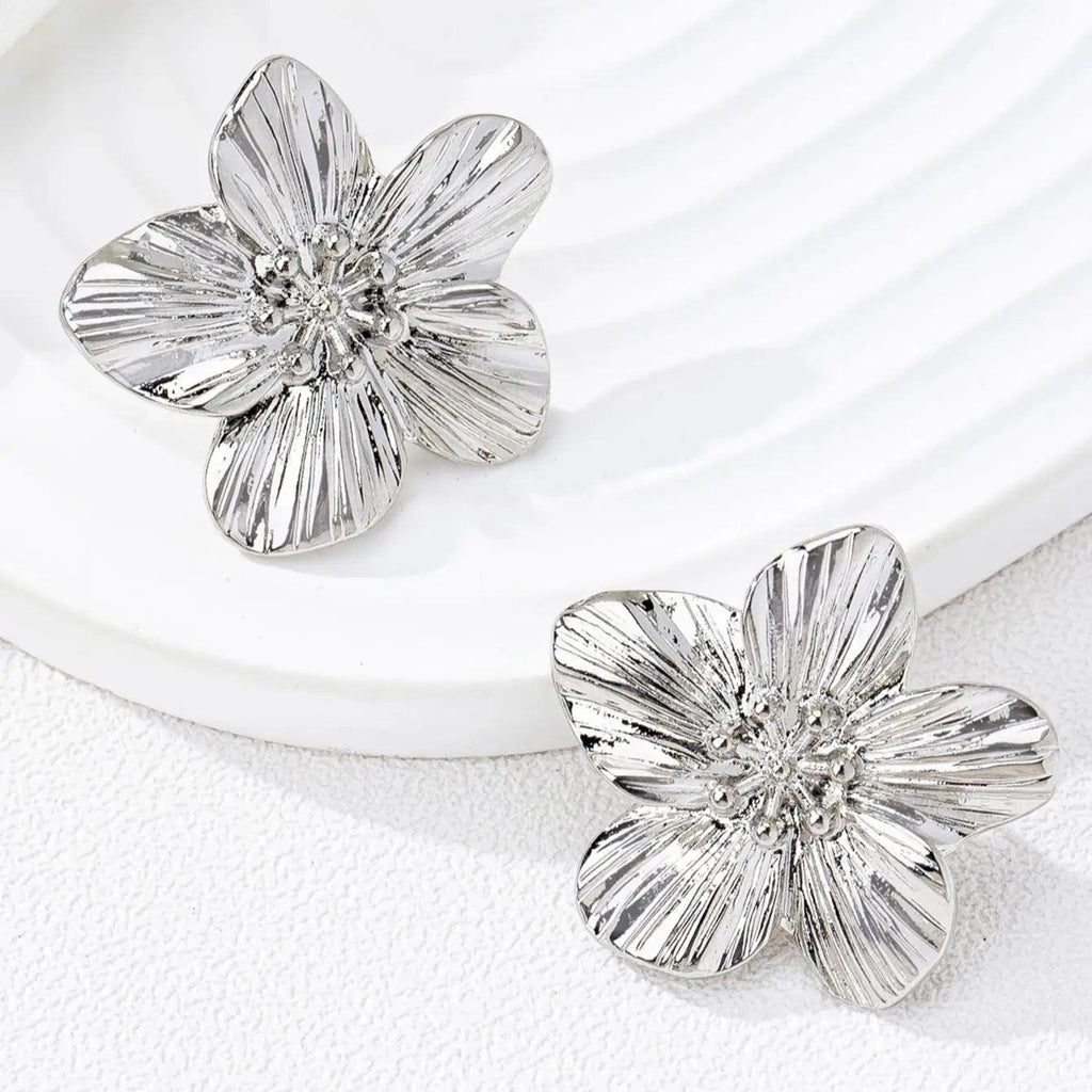 WOLZI Fleur textured silver flower stud earrings on a white ceramic tray
