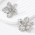 WOLZI Fleur textured silver flower stud earrings on a white ceramic tray