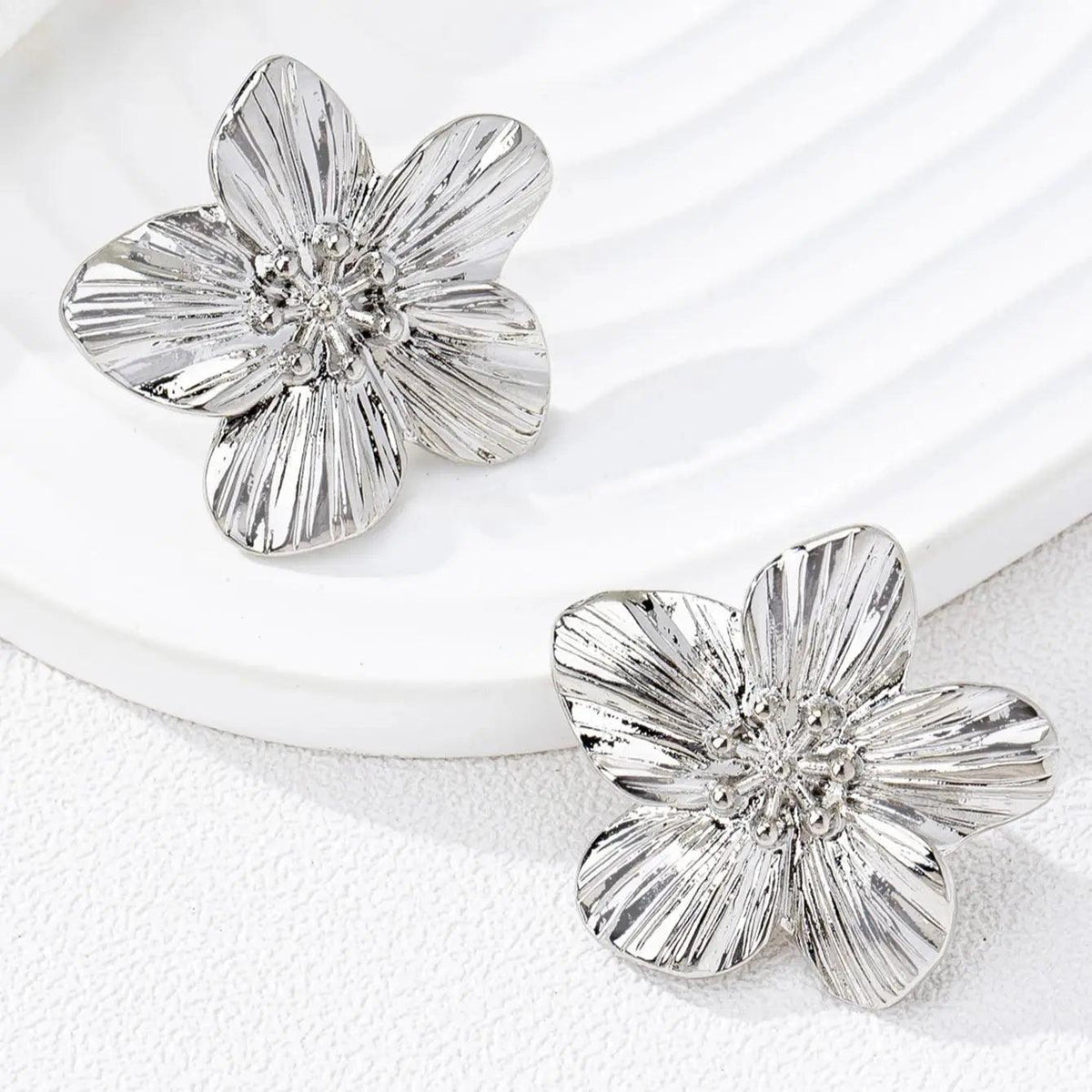 WOLZI Fleur textured silver flower stud earrings on a white ceramic tray