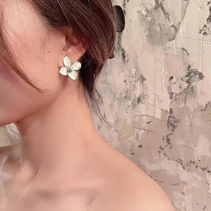 WOLZI Flora Glazed Flower Earrings in white floral design worn by a woman.