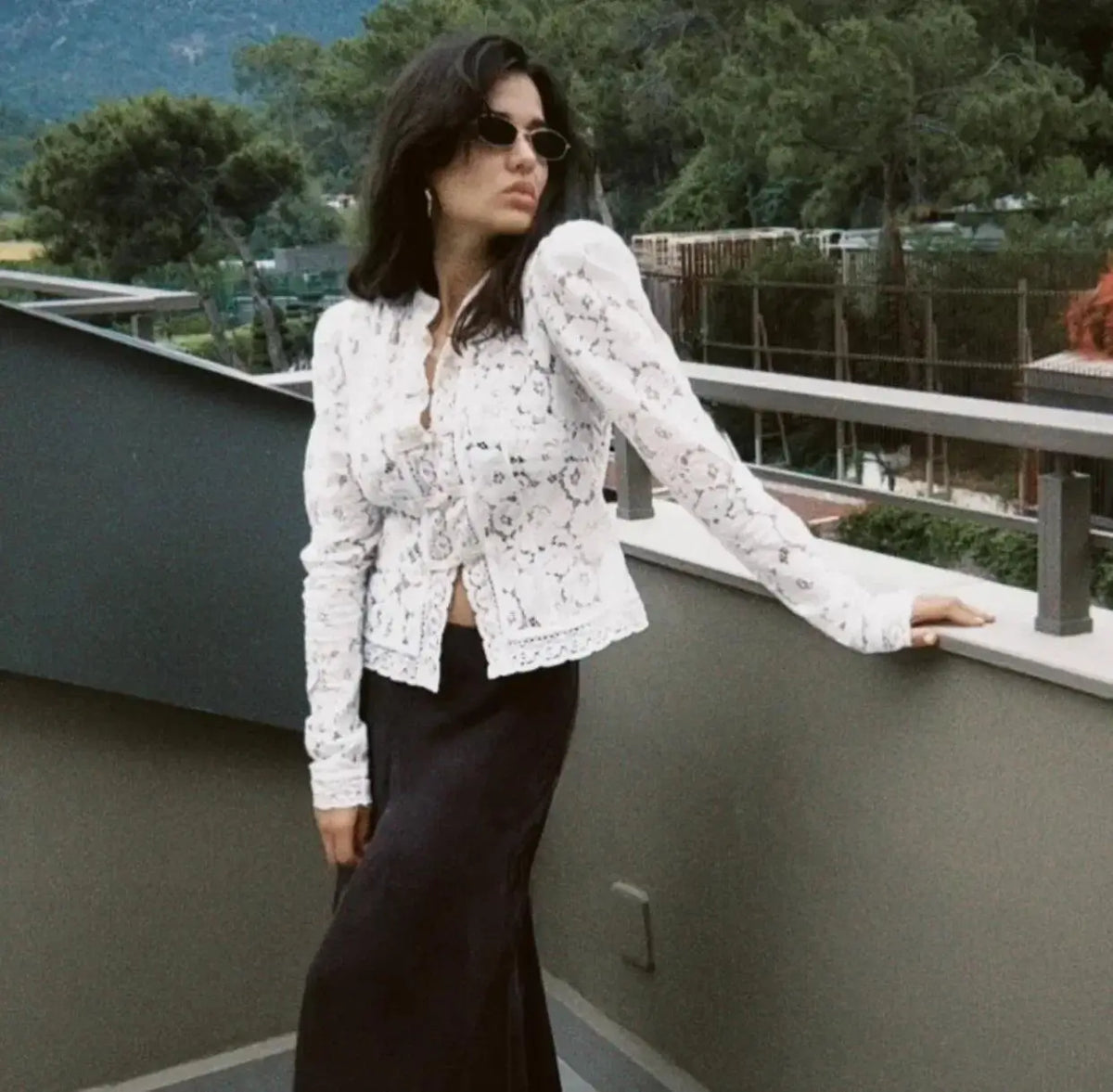 Woman wearing WOLZI Fontaine Lace Blouse in white with long sleeves and black skirt.