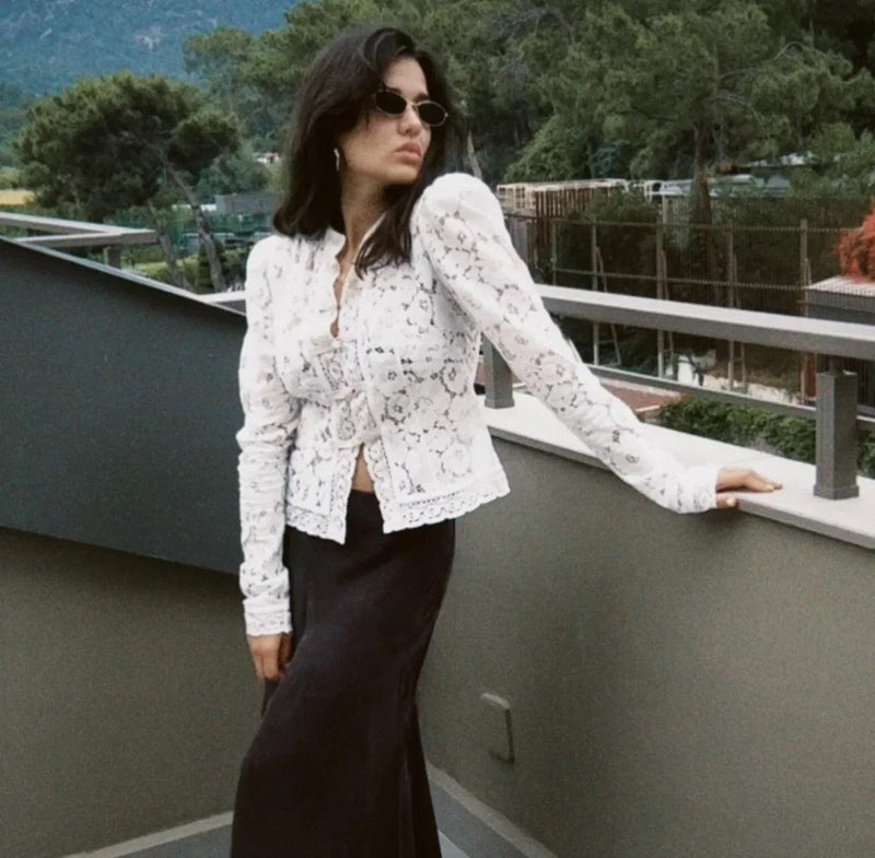Woman wearing WOLZI Fontaine Lace Blouse in white with long sleeves and black skirt.