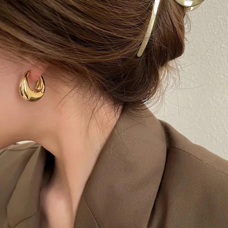 Aurelle sculpted oval gold earrings worn by a woman
