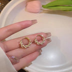 WOLZI Lumi Pearl Circle Stud Earrings held in a hand, featuring gold hoops with small pearls.
