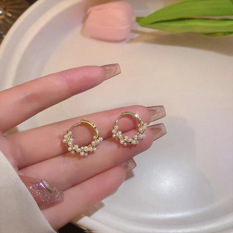 WOLZI Lumi Pearl Circle Stud Earrings held in a hand, featuring gold hoops with small pearls.