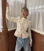 Woman wearing WOLZI Fontaine Lace Blouse in beige with long sleeves and floral patterns.