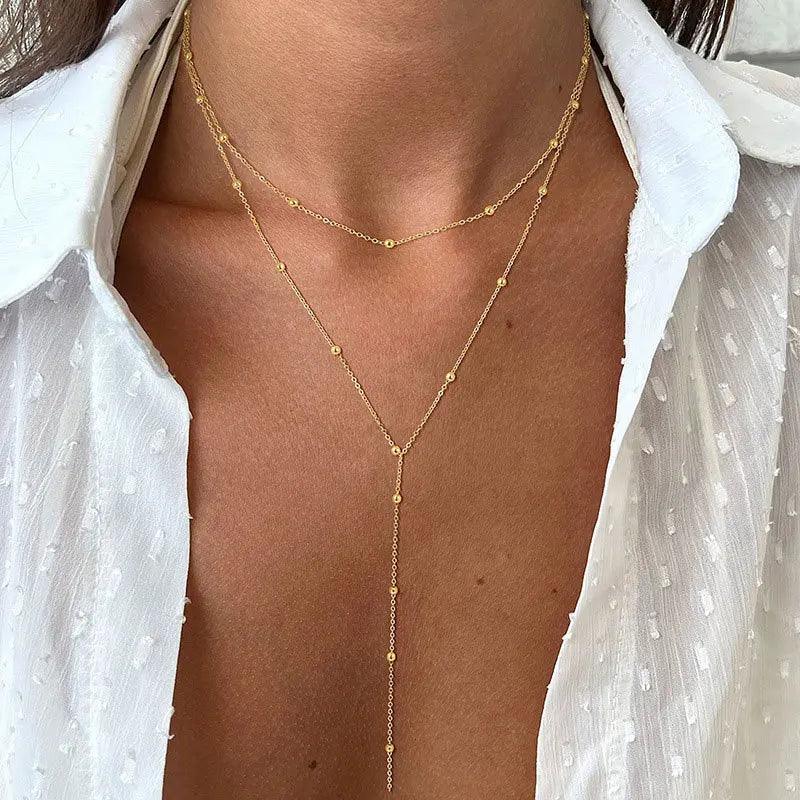 WOLZI Solara Tassel Layered Necklace in gold worn with a white blouse