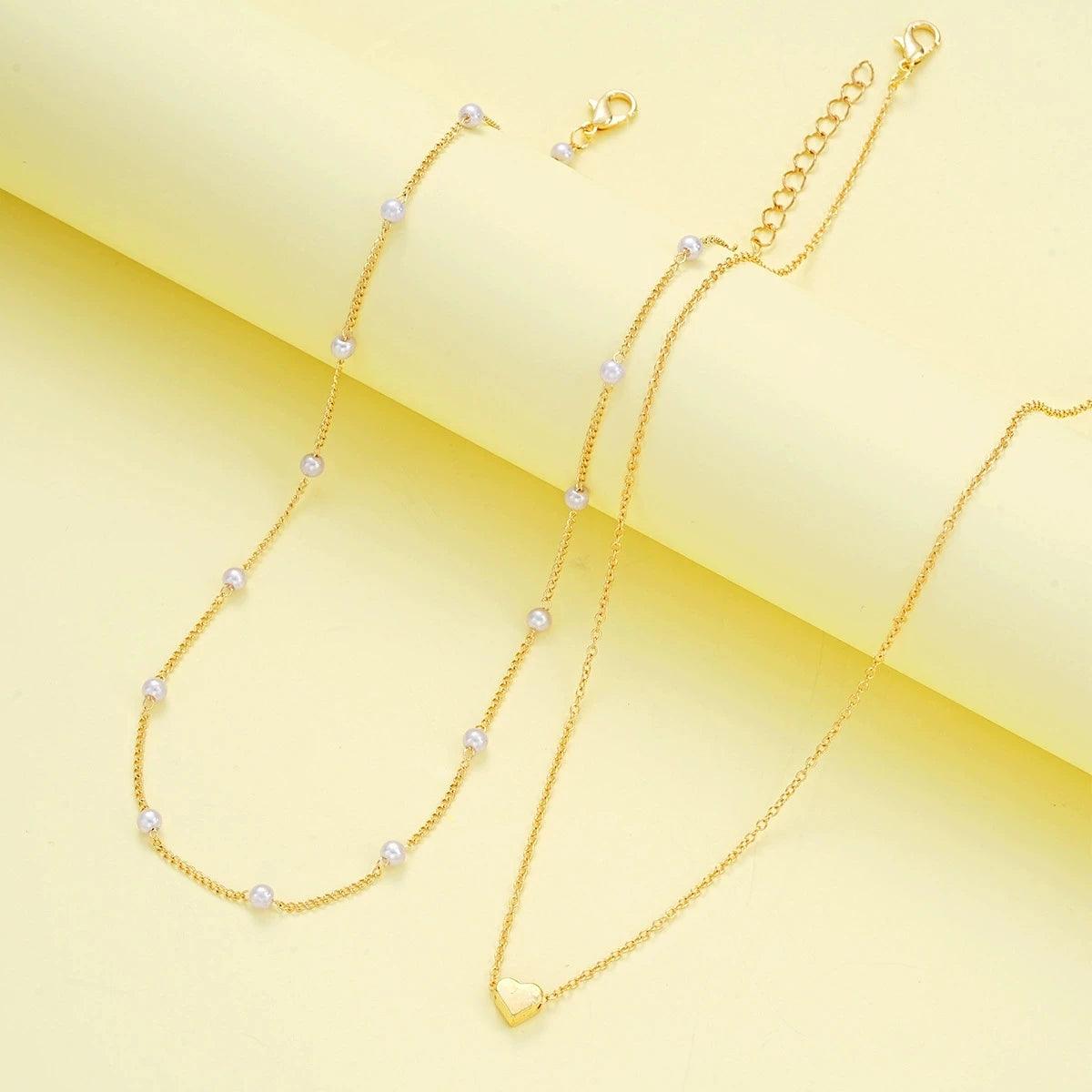 WOLZI Amorette pearl and gold heart jewelry set on a yellow background