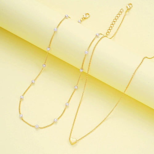 WOLZI Amorette pearl and gold heart jewelry set on a yellow background