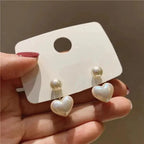 WOLZI Amelie Heart Pearl Earrings featuring white heart-shaped pearls on a white display card.