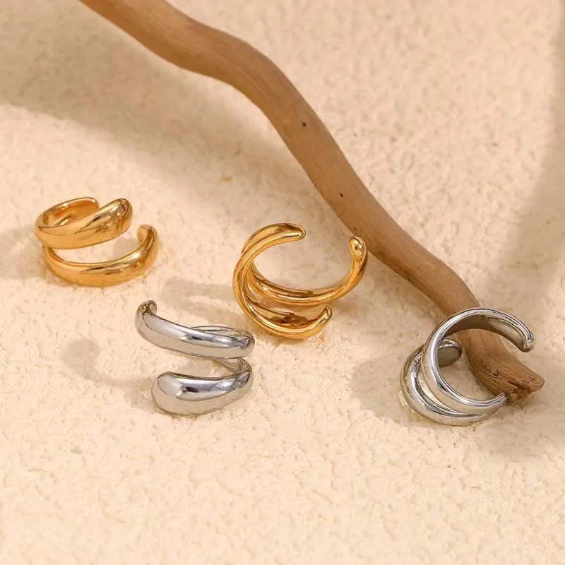 Aria Sculpted Ear Cuff by WOLZI in gold and silver tones displayed on a wooden branch.