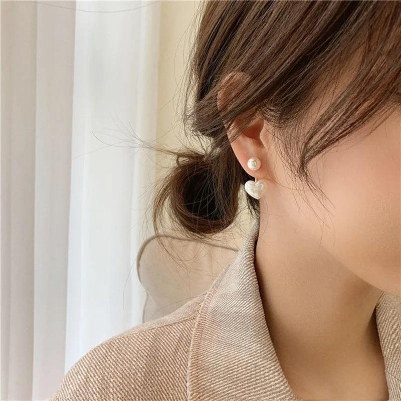 WOLZI Amelie Heart Pearl Earrings worn by a woman